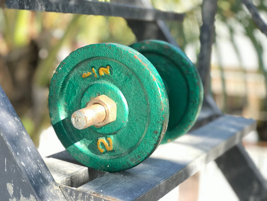 a green dumbbell sitting on top of a metal bench