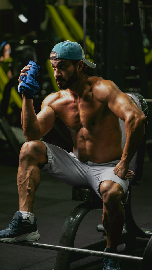a shirtless man sitting on a bench in a gym