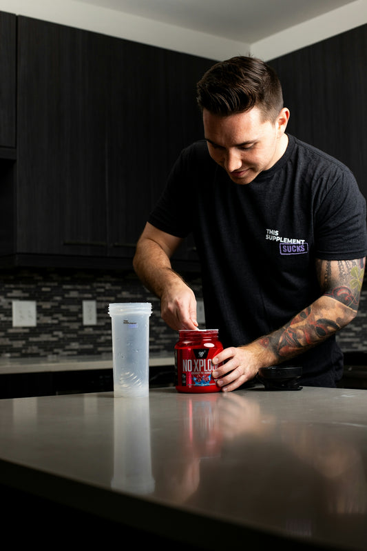 a man standing at a kitchen counter with a can of protein drink
