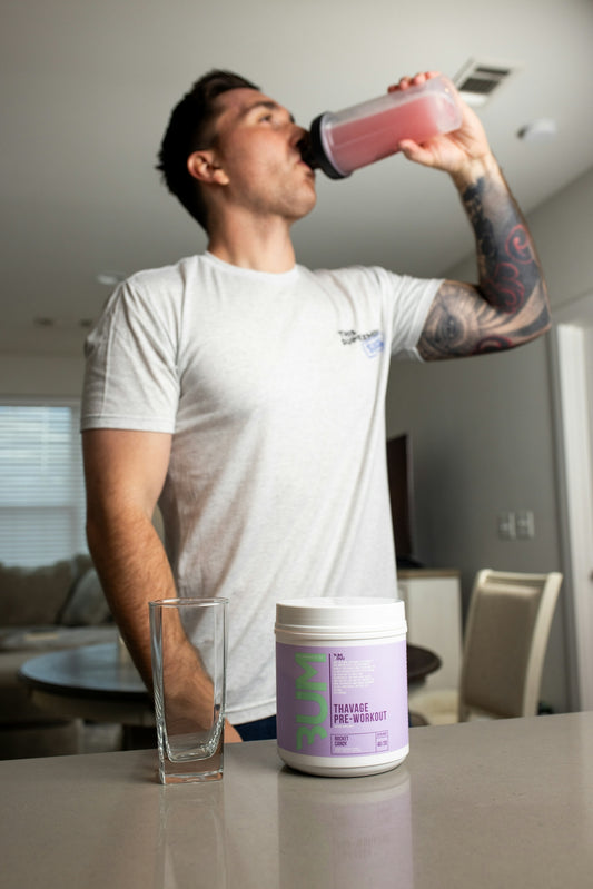 a man drinking from a pink bottle next to a glass of water