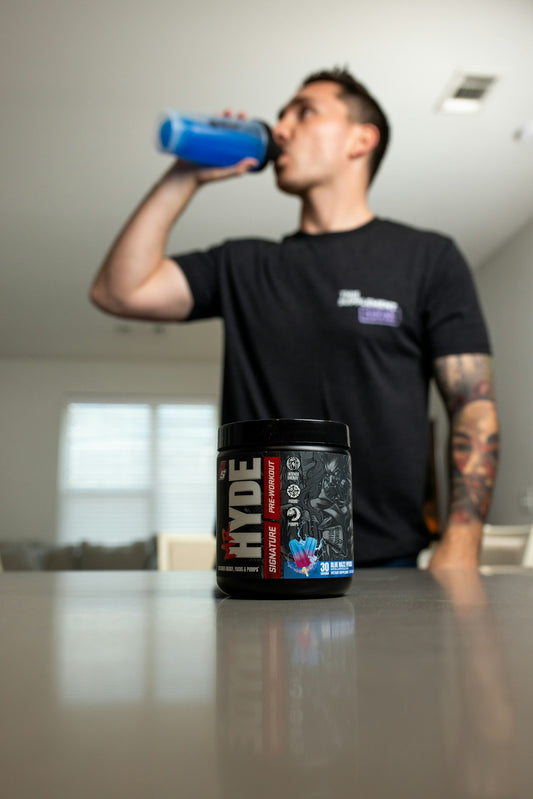 a man drinking from a blue bottle on top of a counter