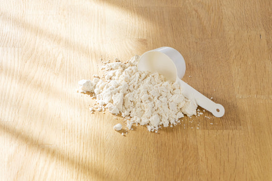 A scoop of protein powder on a wooden surface.