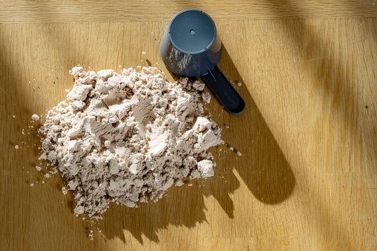 Scoop of protein powder on a wooden surface