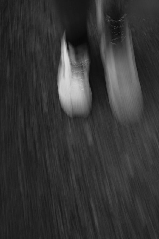 Motion blurred feet in sneakers running on a dark asphalt surface